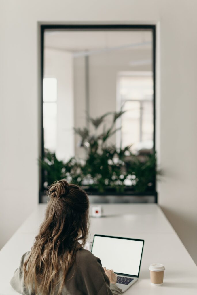 lsitting and working on the laptop and coffee on the desk, mirror in the background